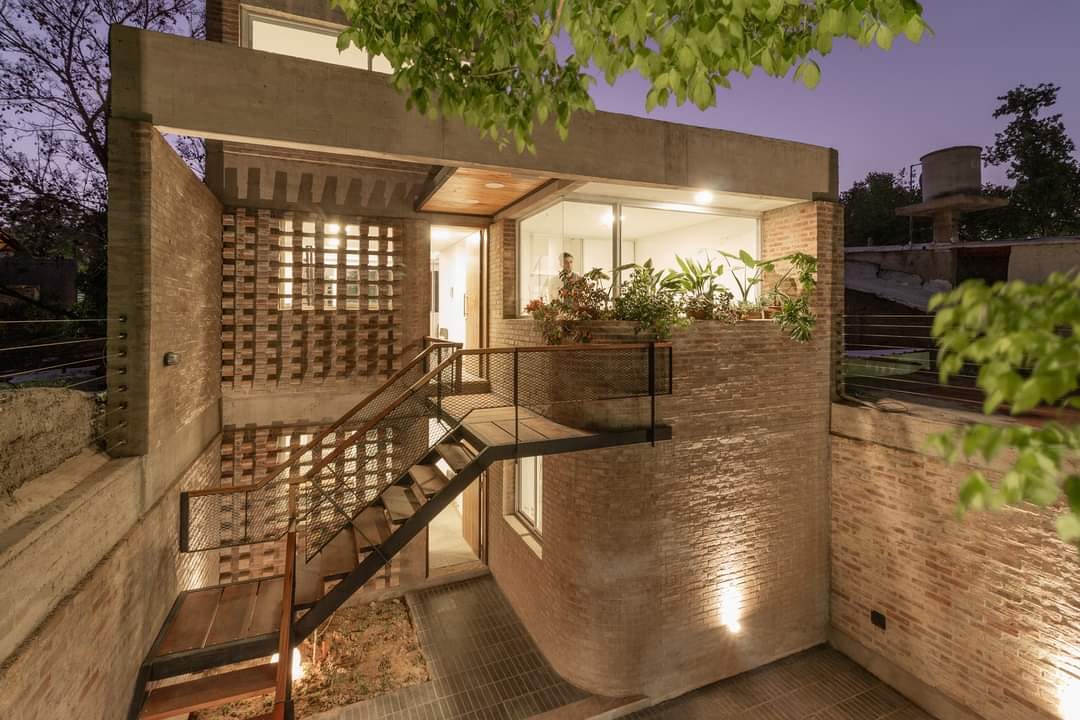 Casa de ladrillo con escalera metálica vista nocturna